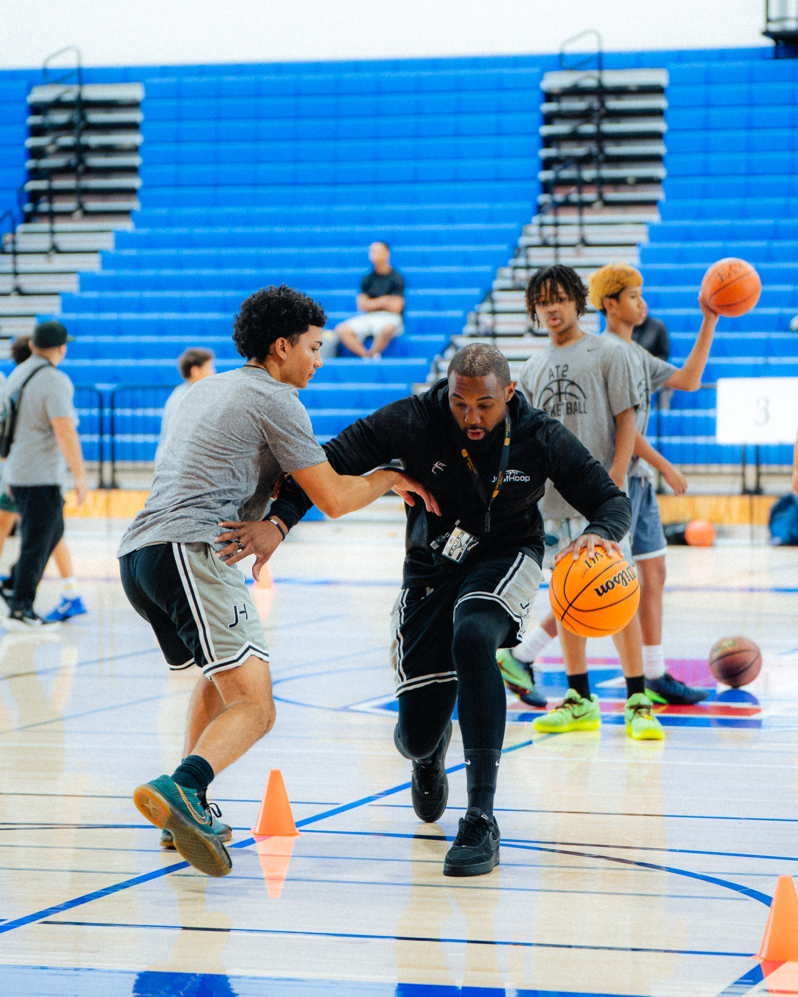 A JustHoop coach demonstrating a cone drill with players at AT2