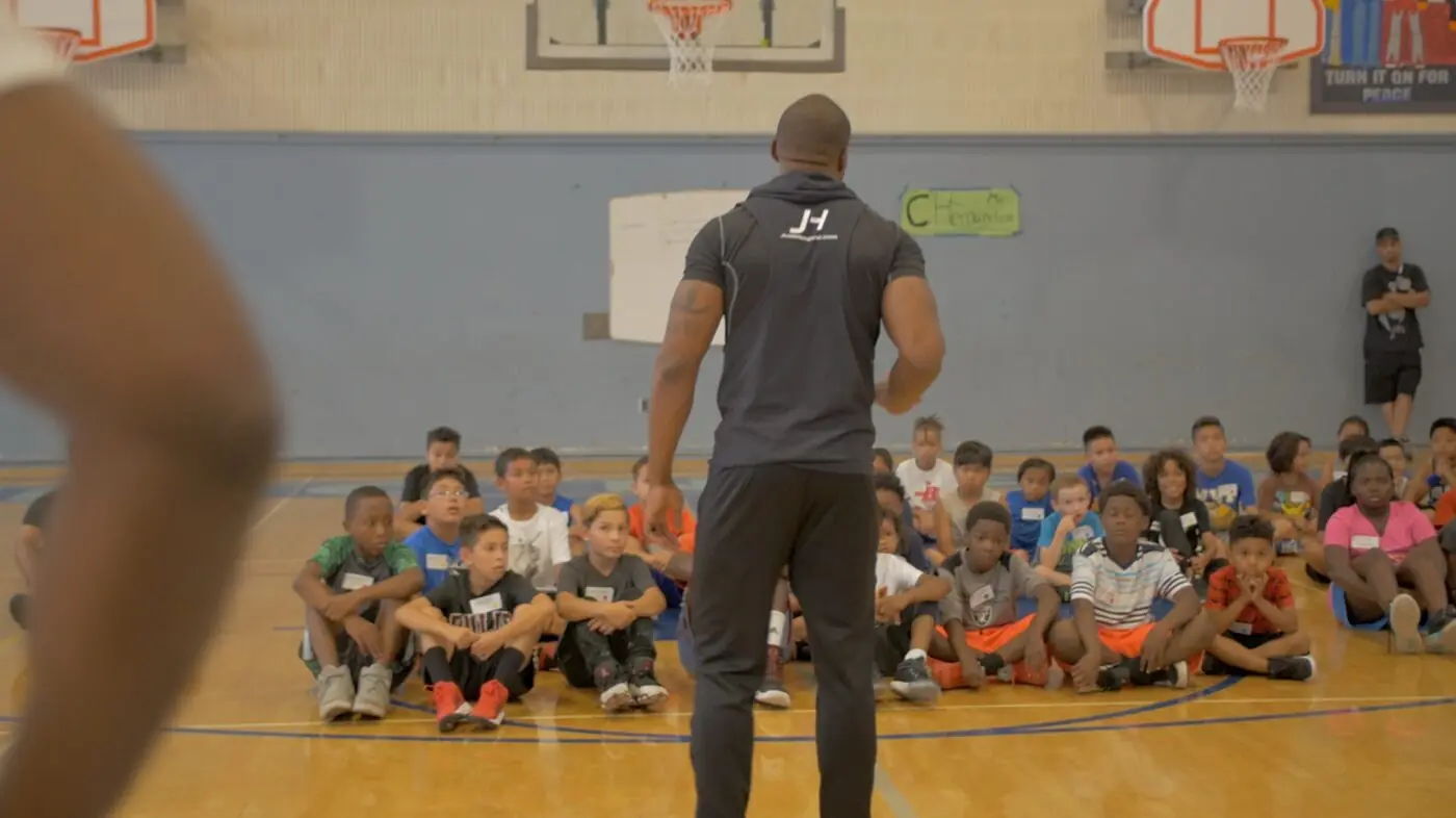 A Just Hoop coach addressing a gym full of seated campers